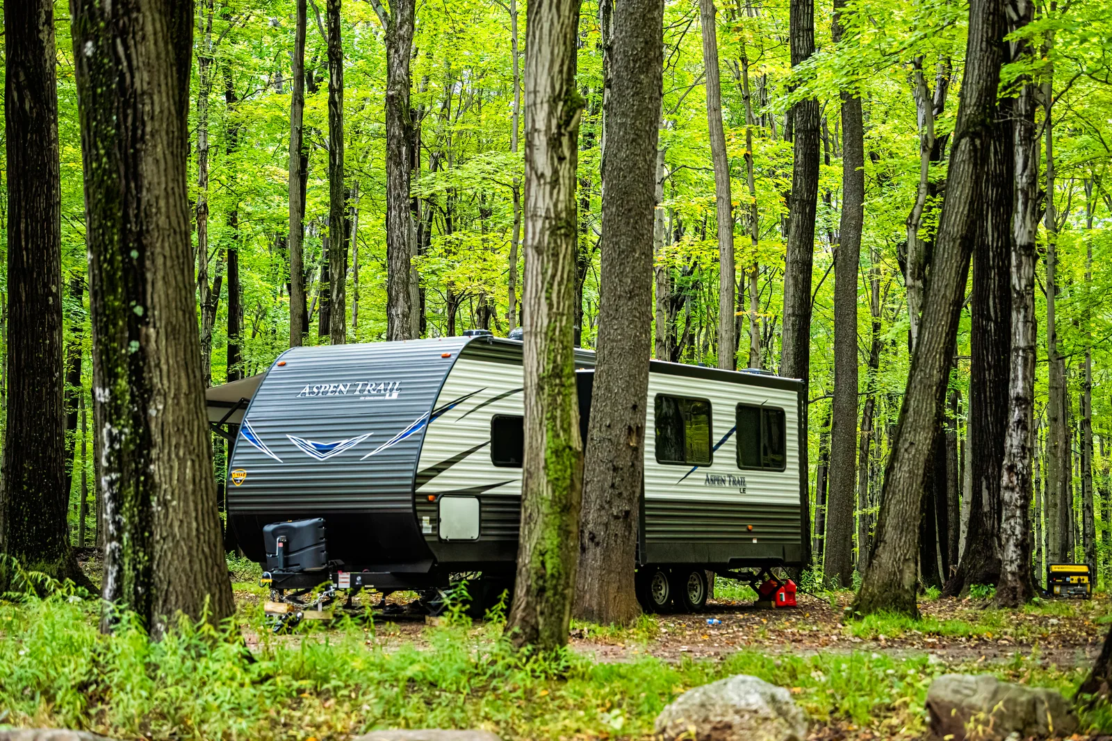 Motorhomes and travel trailers parked at shaded full-hookup sites in a busy campground