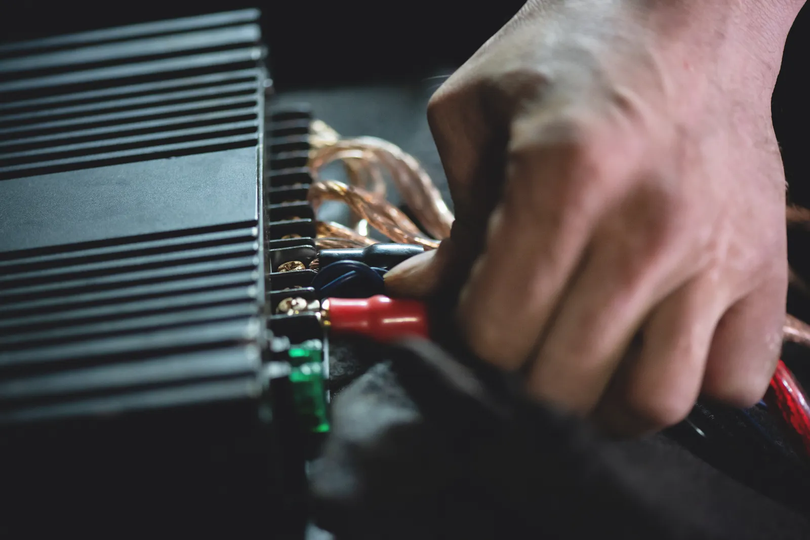 Technician installing a subwoofer and amplifier in the trunk of a car at a car audio shop