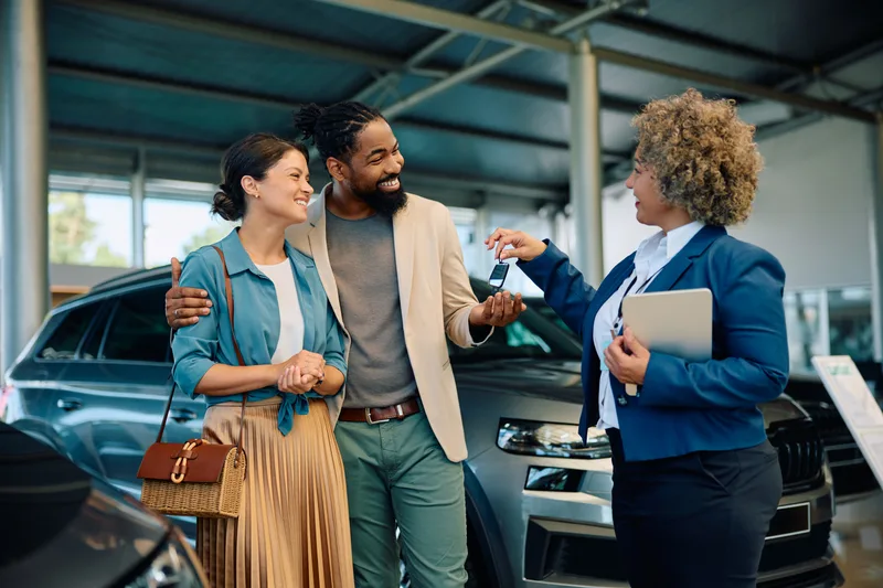 Salesperson congratulating a customer buying a new car at a dealership
