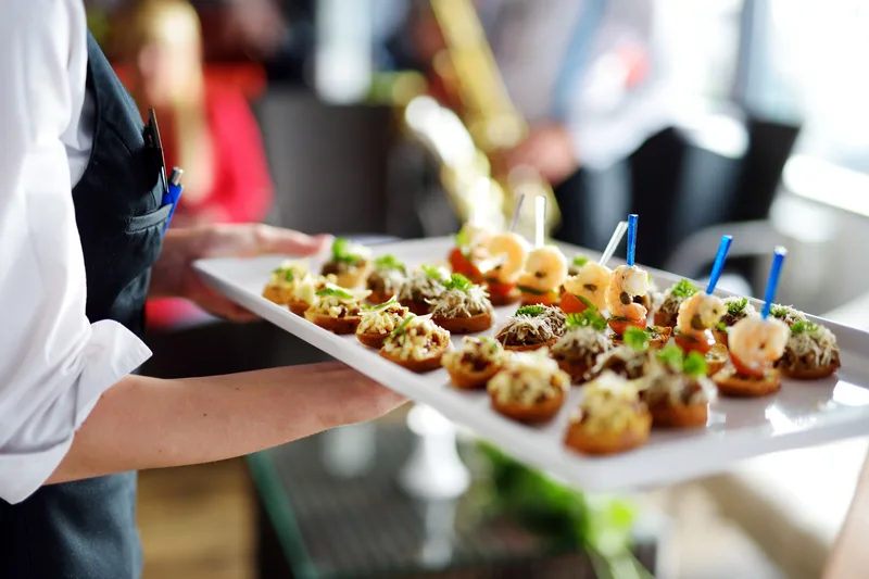 Catering server presenting plated dishes at an event