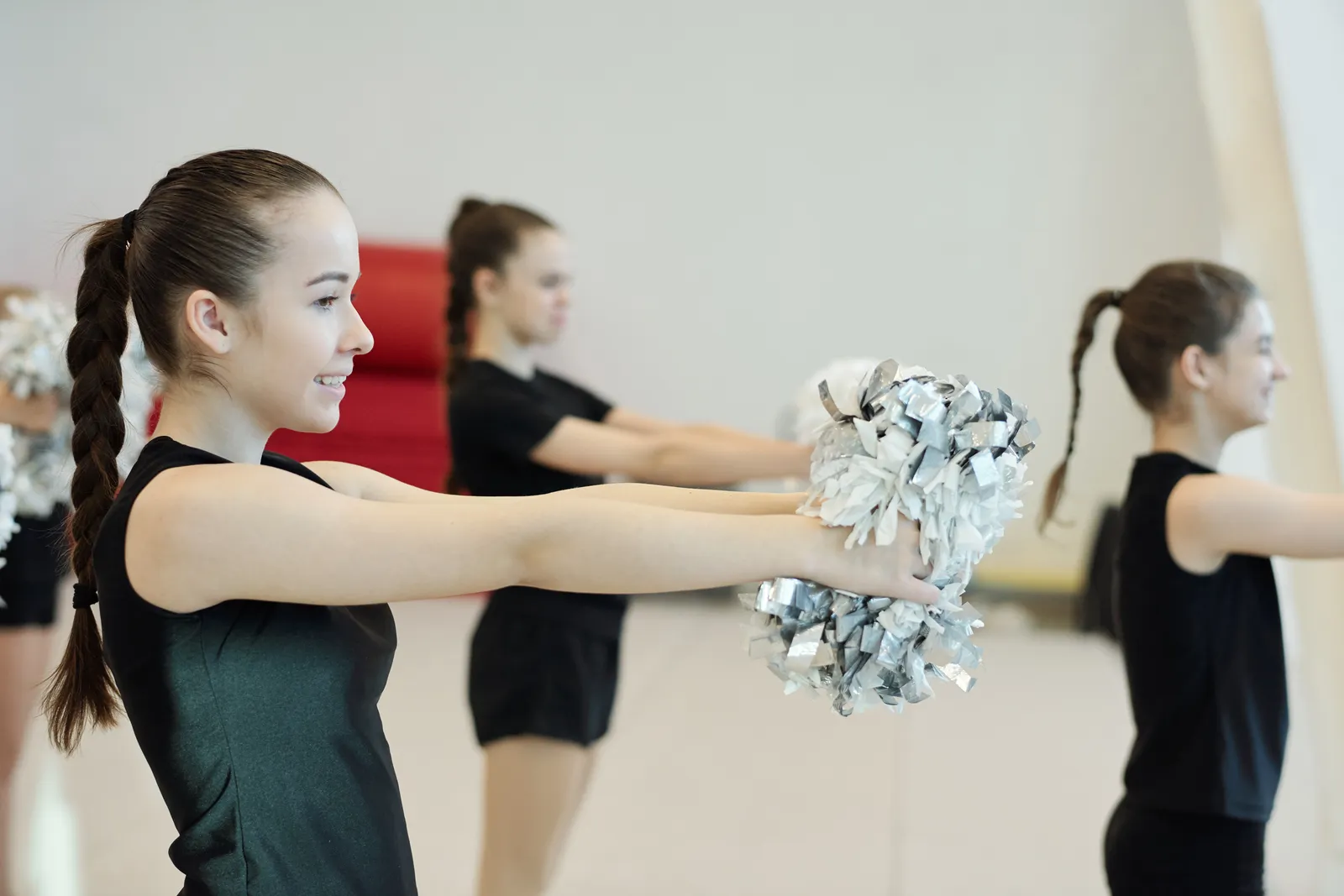 Cheer team practicing a pom routine in the gym