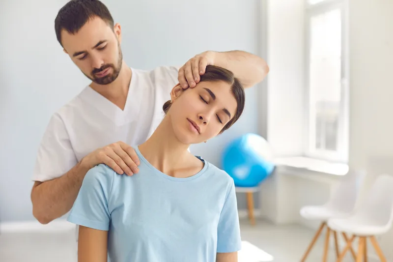 Chiropractor performing a neck adjustment on a patient in a modern clinic