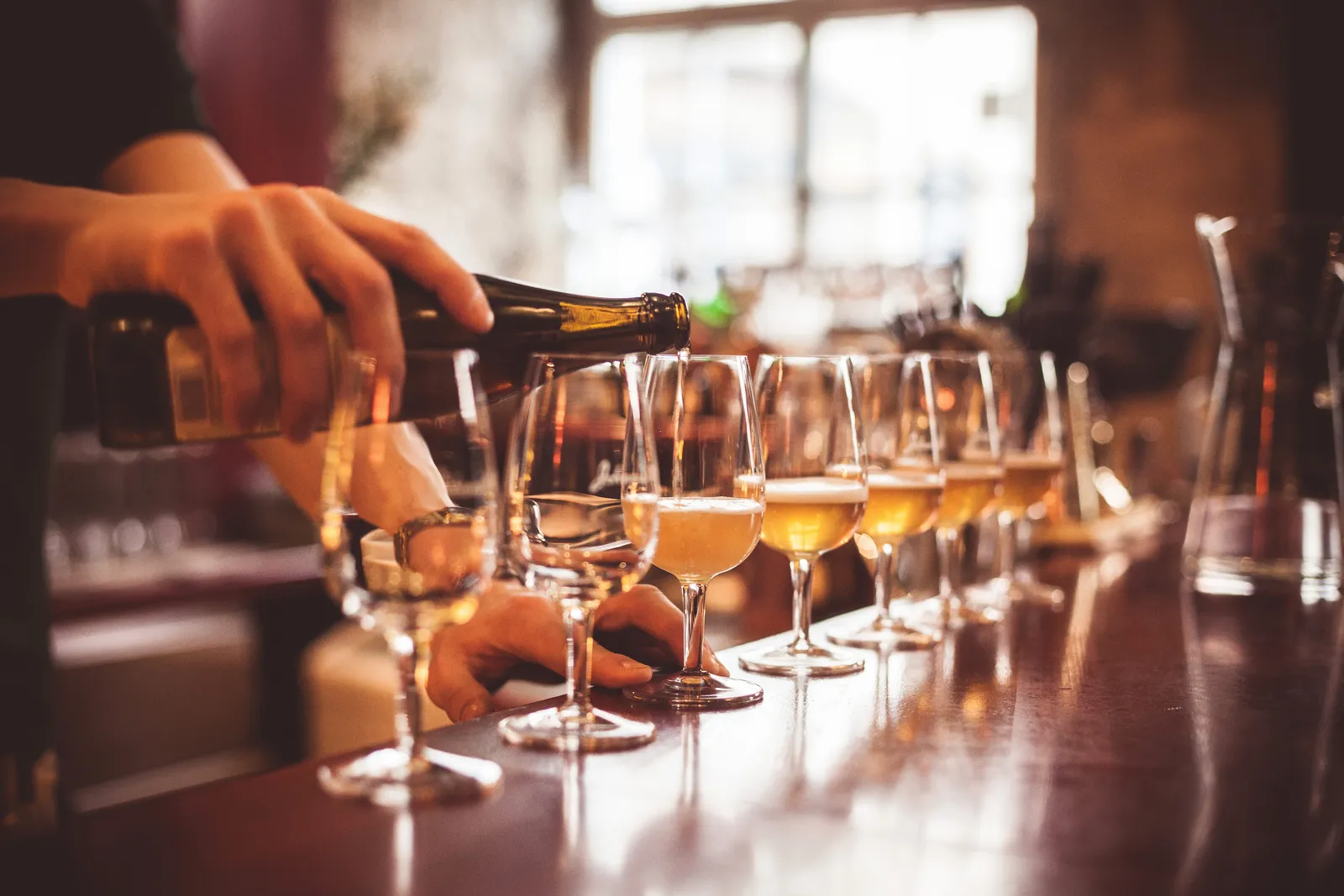Bartender pouring a flight of hard cider into tasting glasses at a cidery and meadery taproom bar