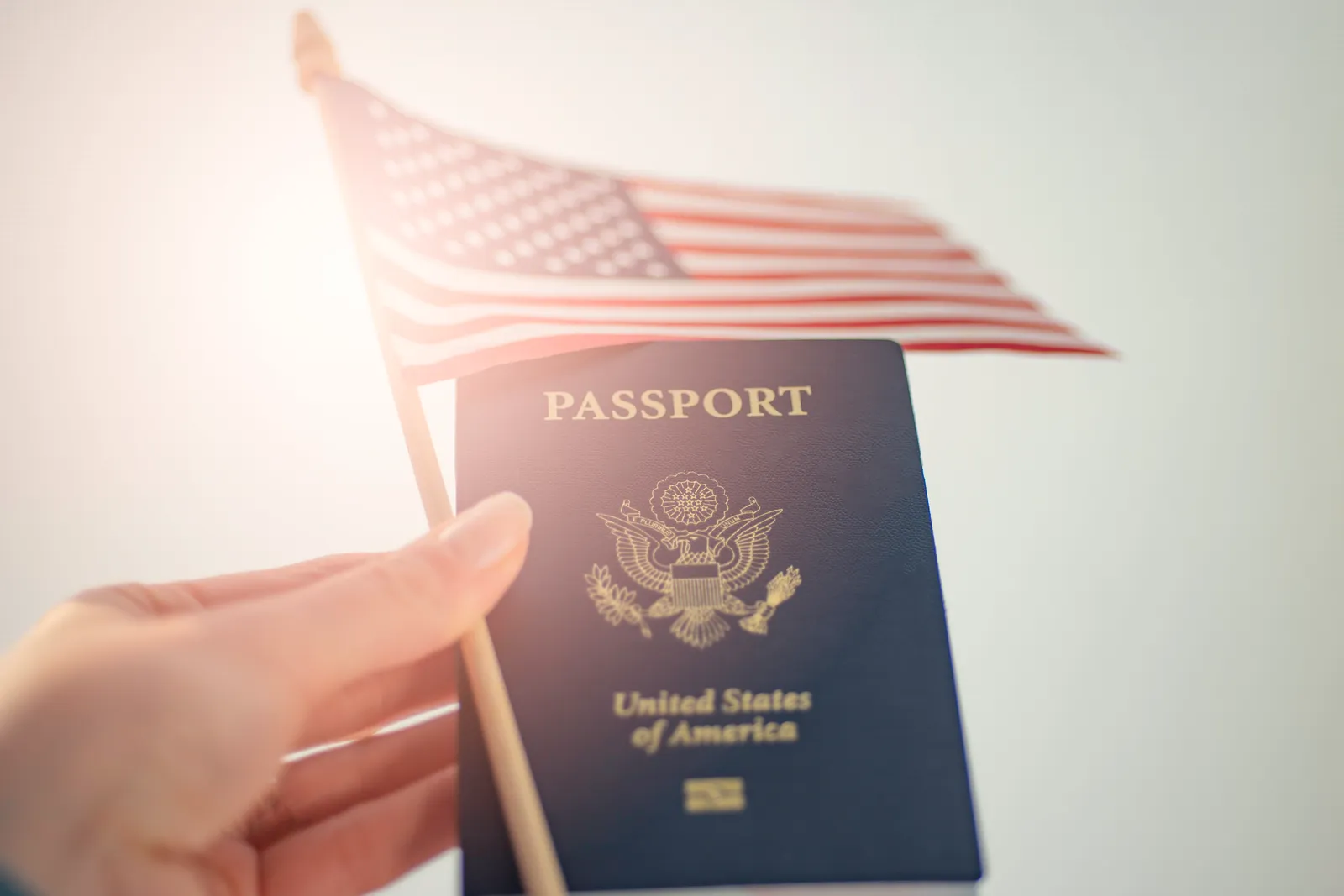 Hand holding a small American flag and a United States passport