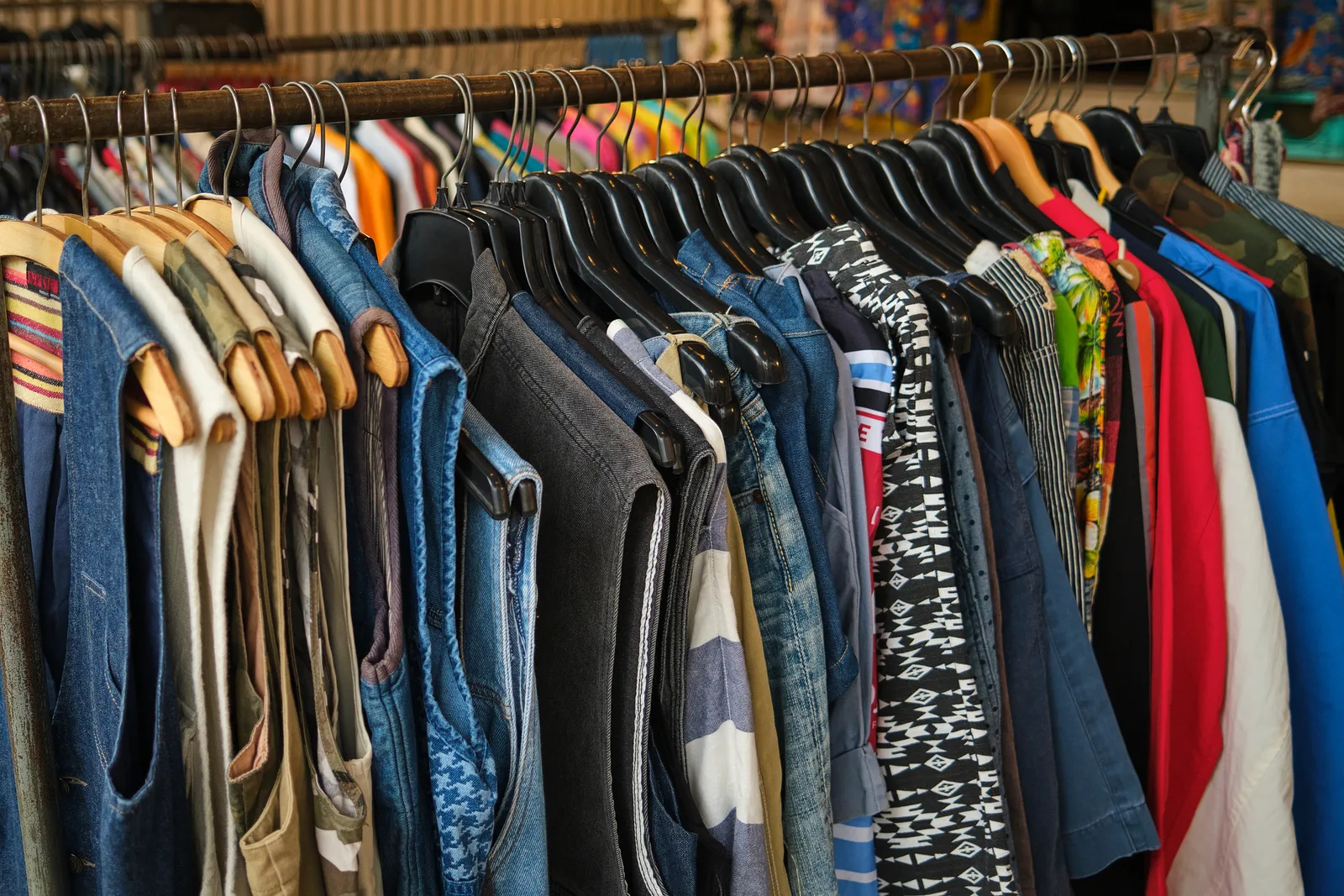 A boutique owner styling a customer beside a rack of new-arrival dresses in a small clothing shop