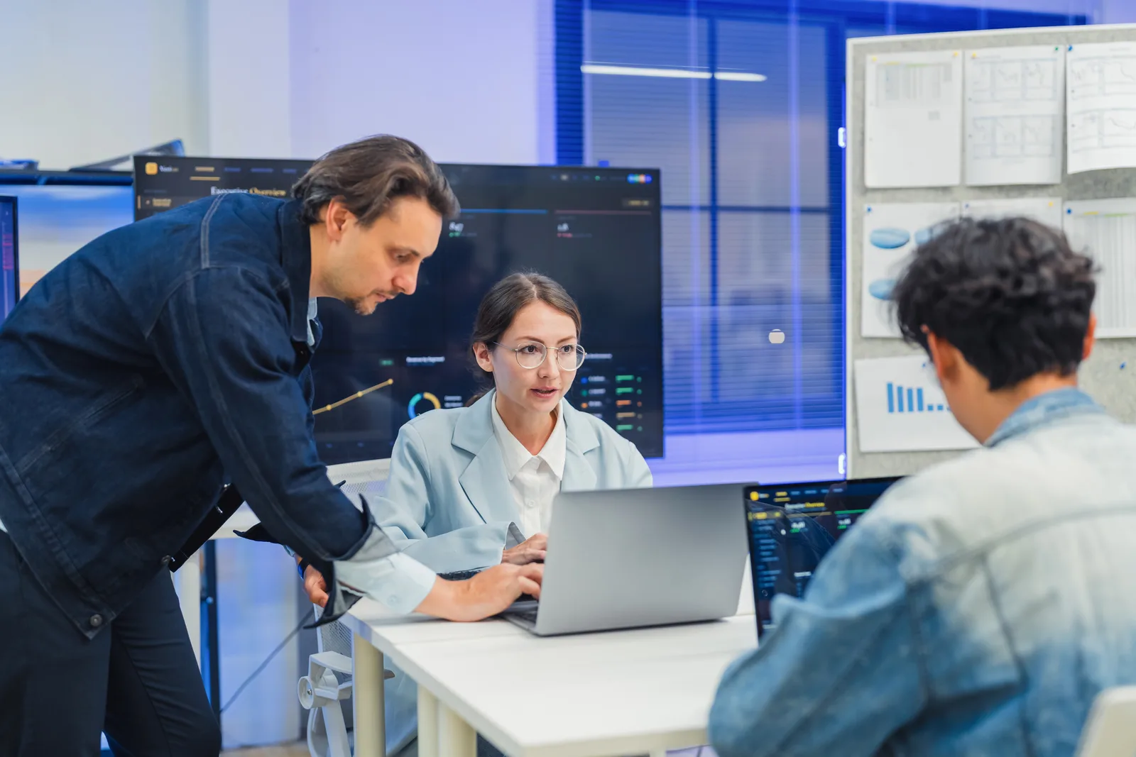 Cloud security team reviewing a multi-cloud misconfiguration and attack-path dashboard together at a laptop in their office