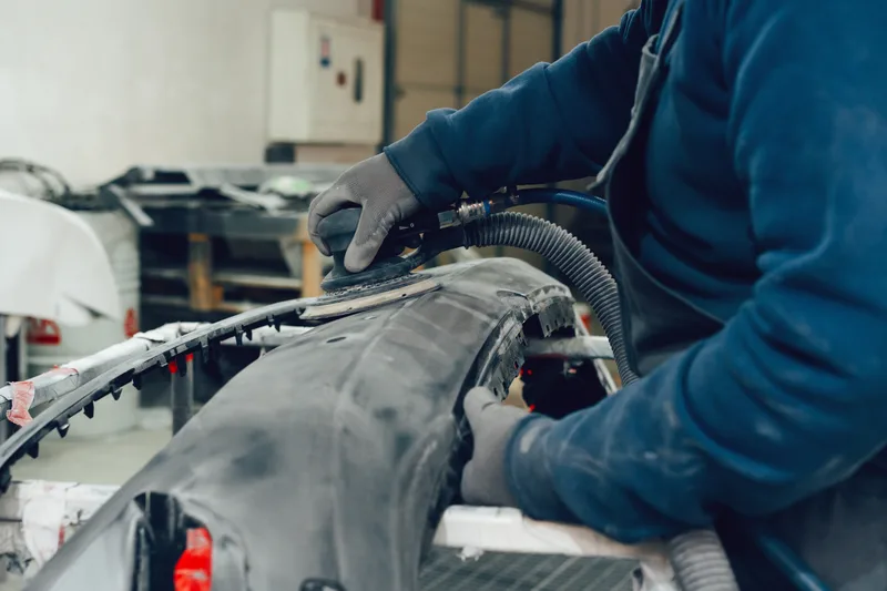 Technician restoring a vehicle body panel at a collision repair centre
