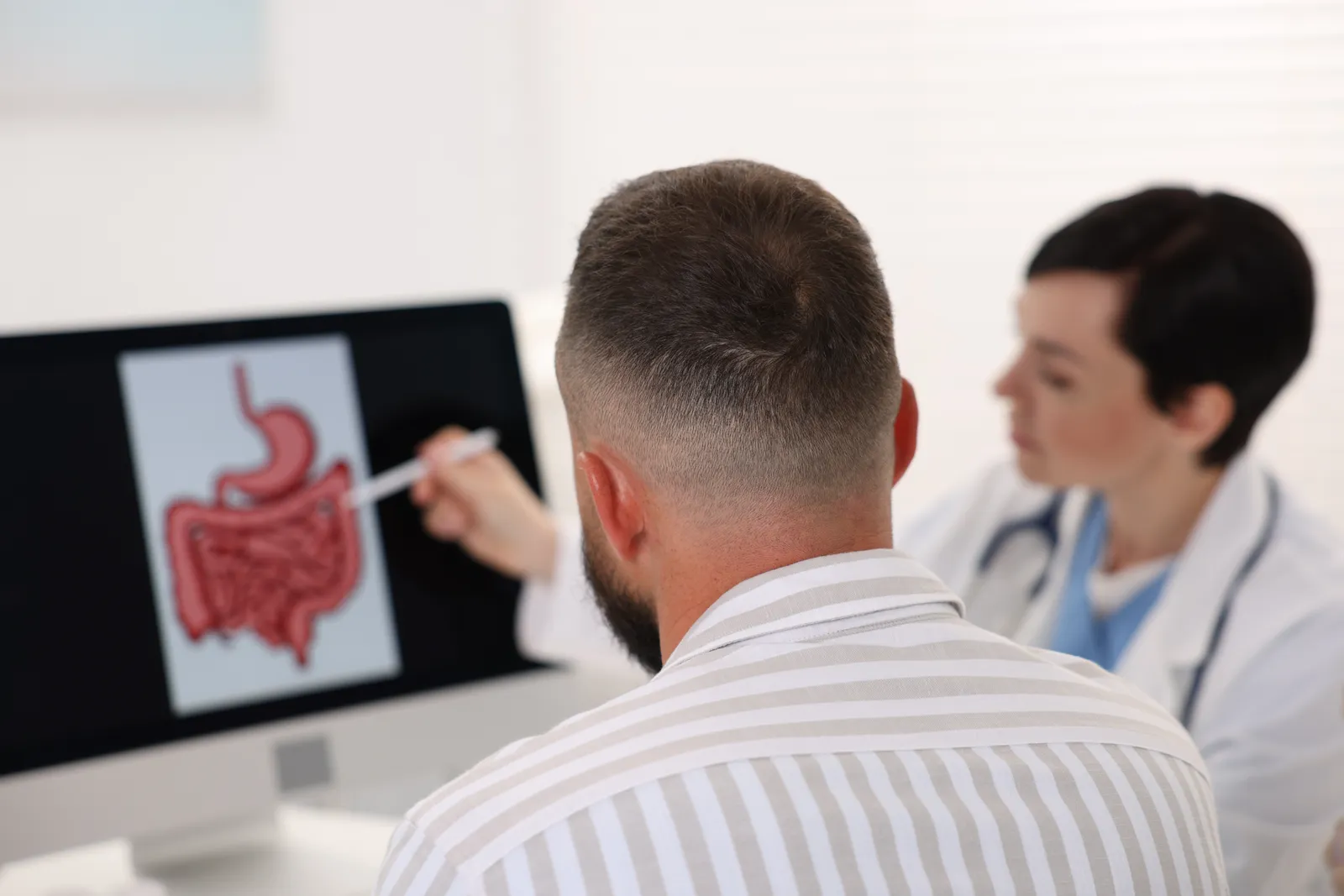 Colorectal surgeon reviewing colonoscopy imaging with a patient during an office consultation