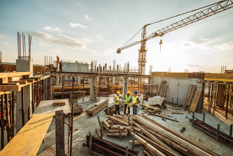 Engineers reviewing plans on a commercial construction site with a crane
