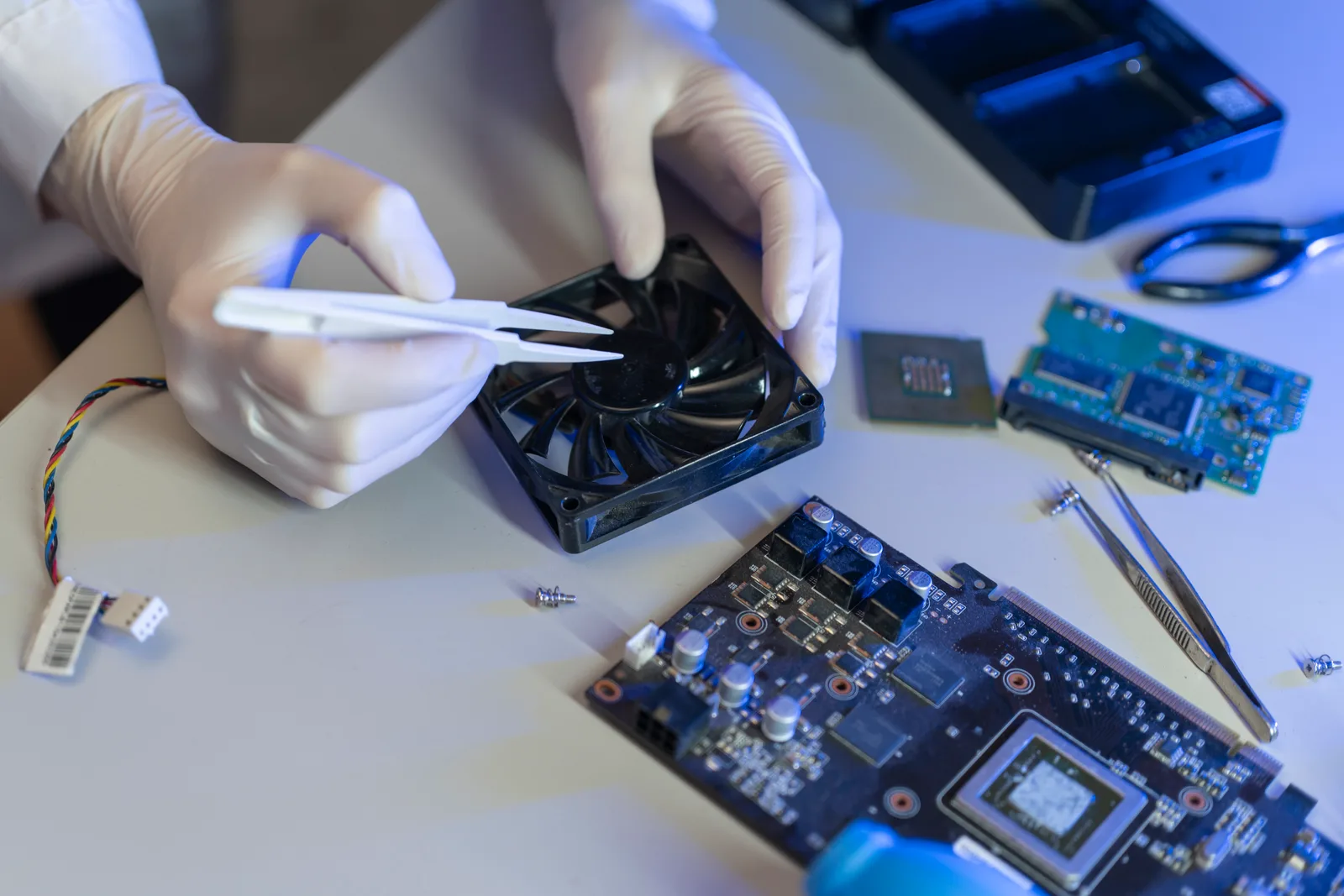 Computer repair technician running diagnostics on an open laptop at a workbench, tools laid out beside it