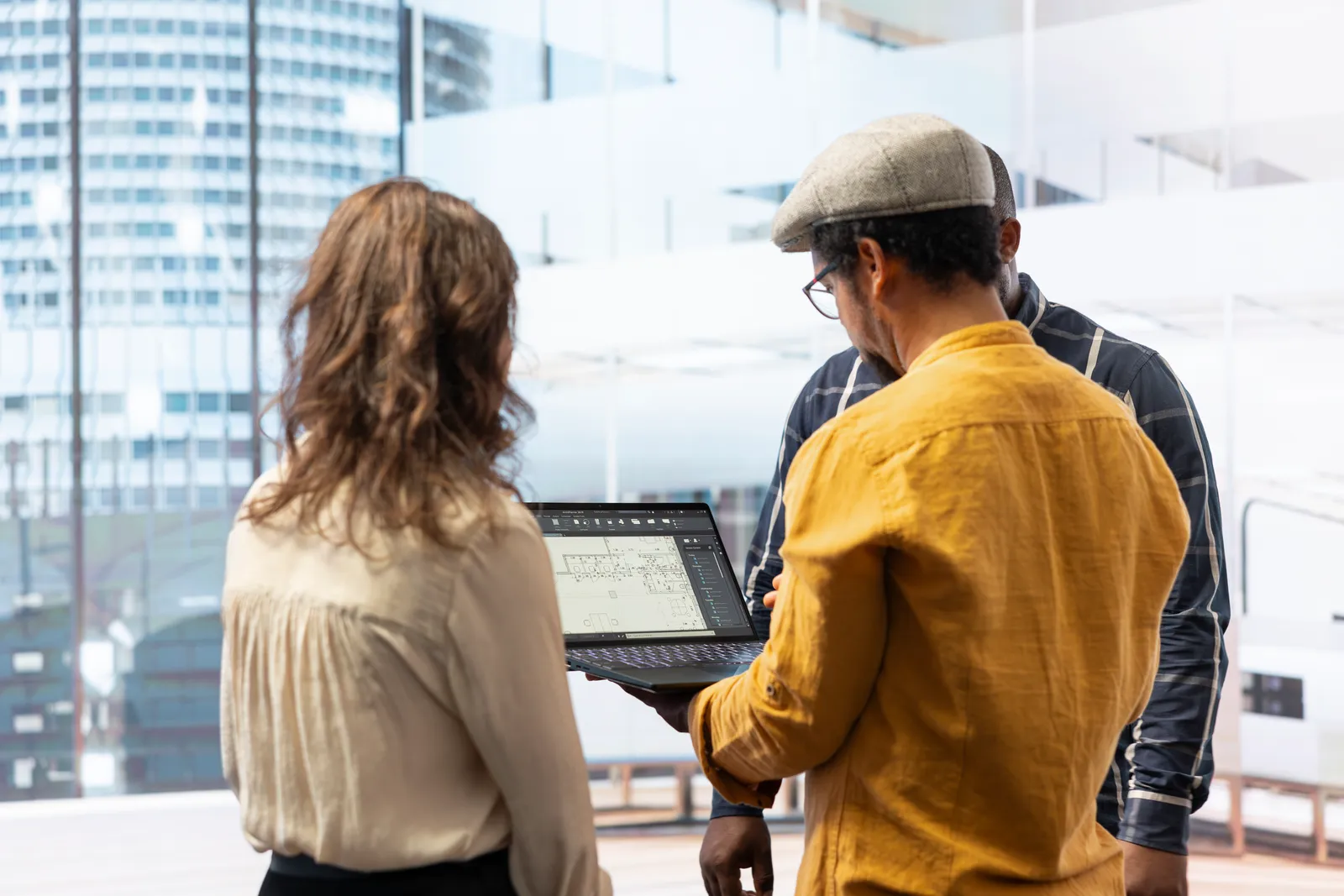 Construction tech team reviewing project data together on a tablet by their office window