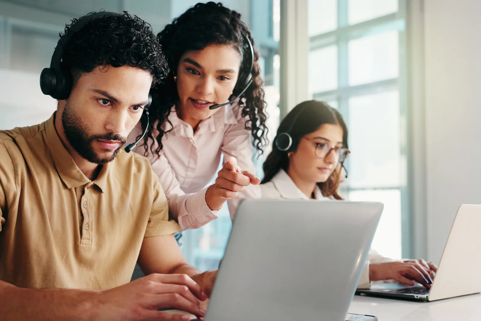 Contact center software team reviewing live call queue and agent performance dashboards together at a laptop in their office