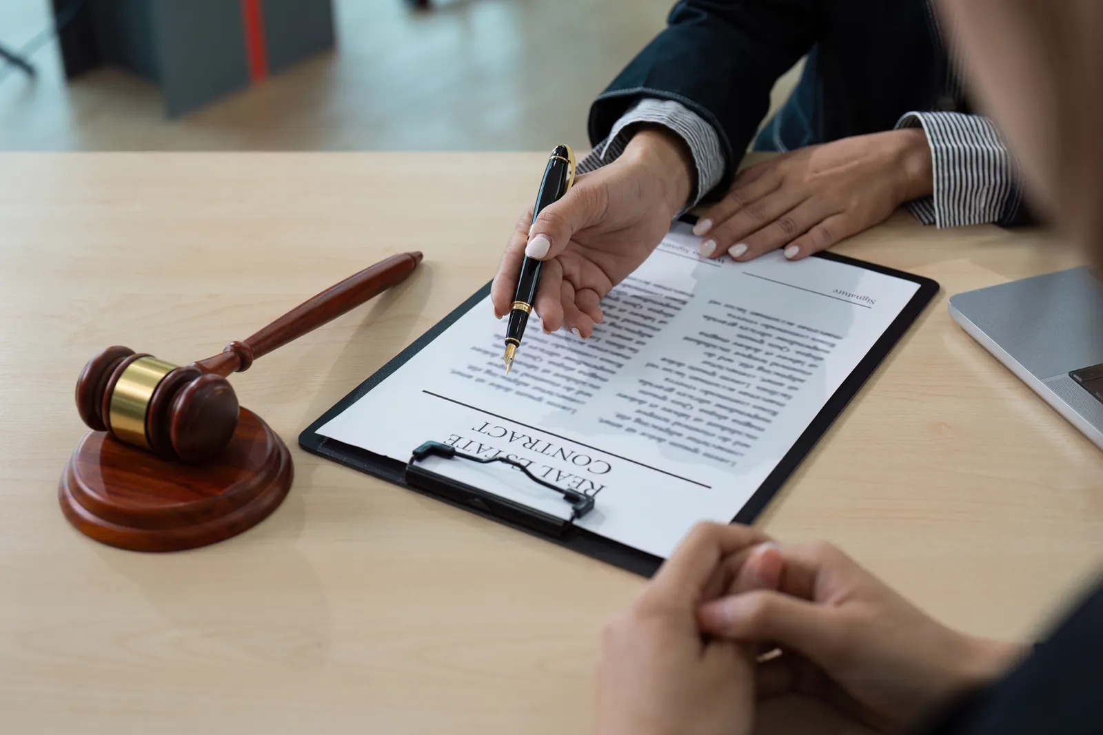 Client signing a copyright agreement beside a gavel at an attorney's desk