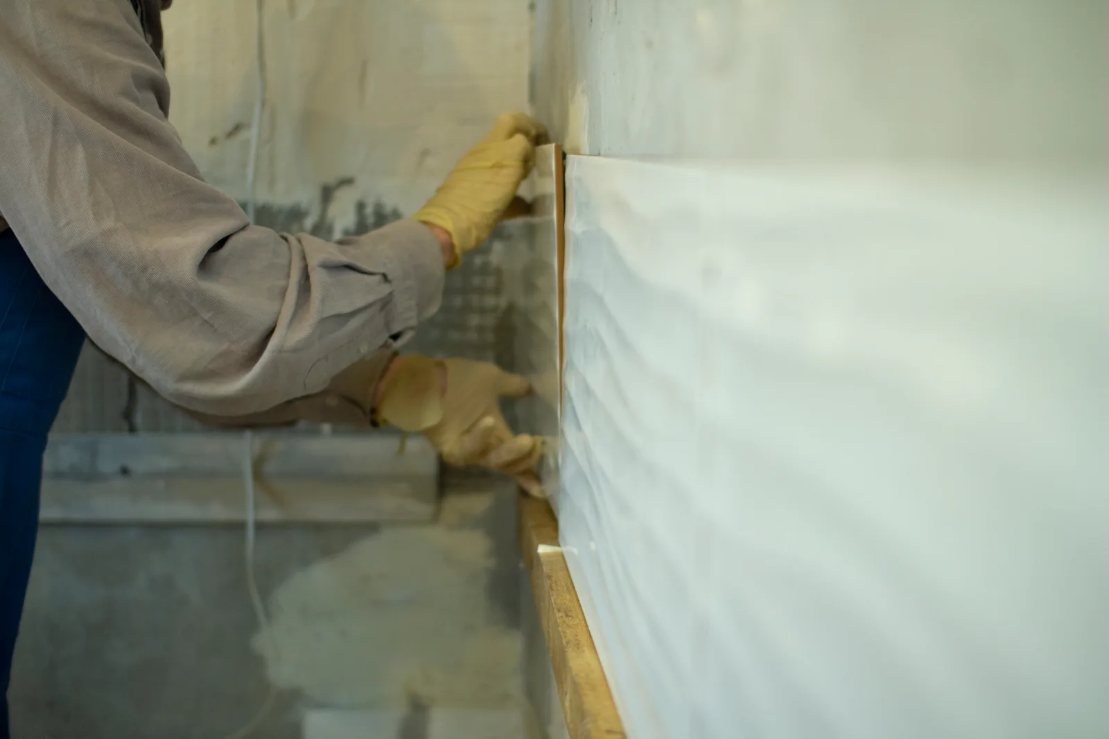 Technician installing a white vapor barrier liner across a crawl space floor and up the foundation walls