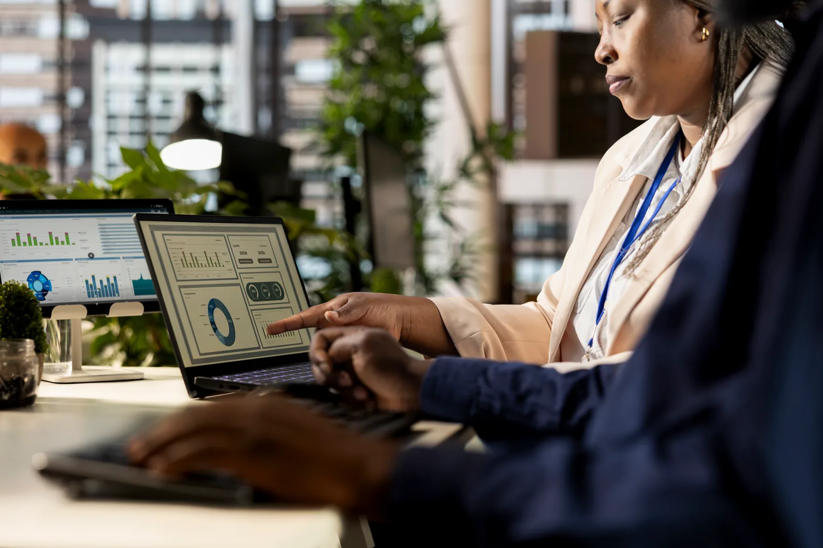 Credit union operations director and IT manager reviewing core banking software account and compliance dashboards together on a laptop in their office