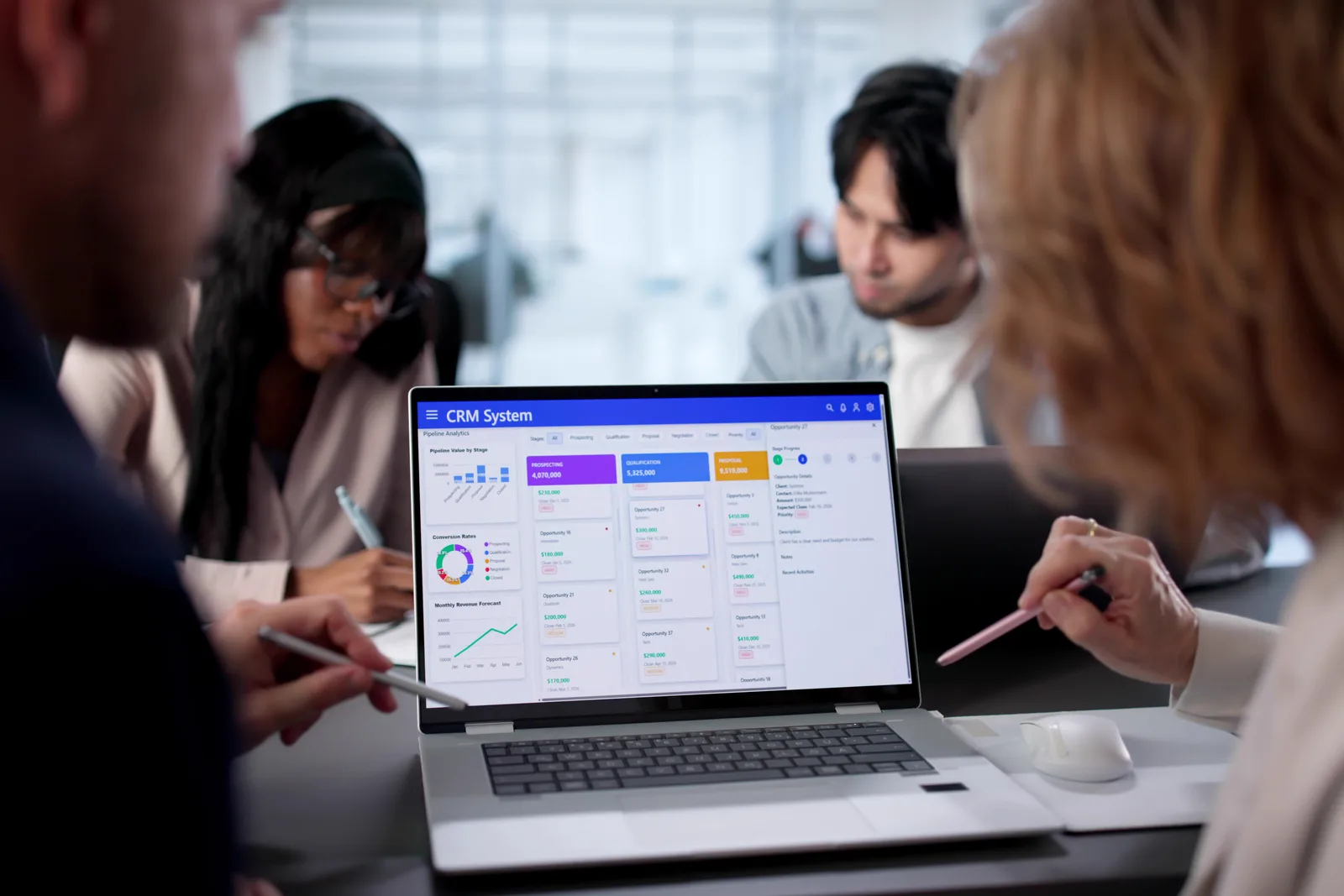 CRM software team reviewing a sales pipeline and trial-signup dashboard together at a laptop in their office