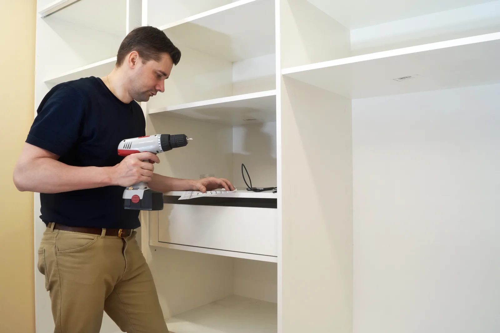 Closet installer fitting shelving in a custom walk-in closet while reviewing the design with the homeowner