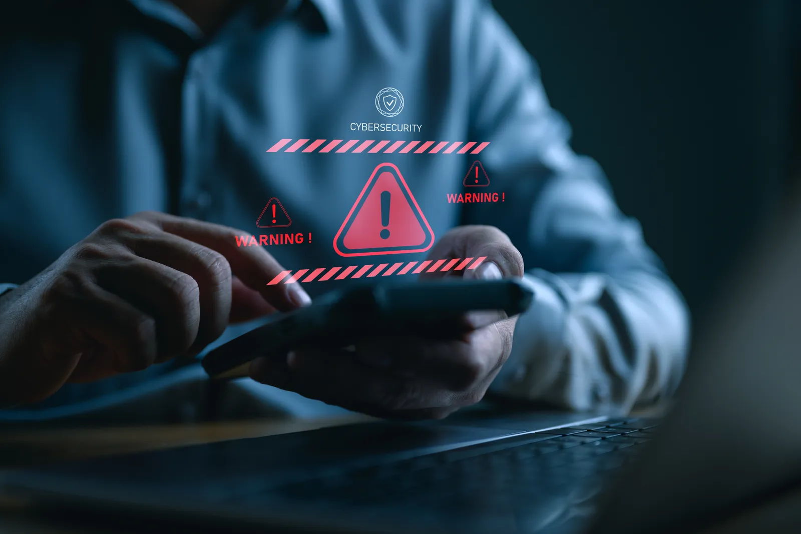 Person at a laptop with data breach warning alerts on the screen