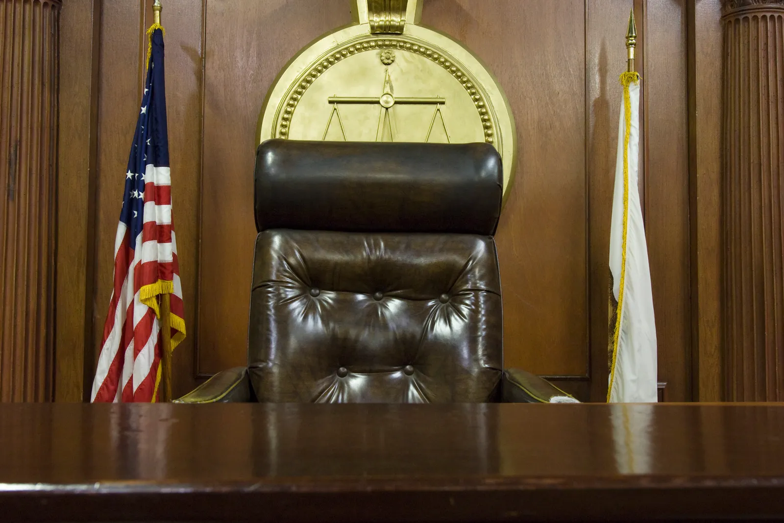 Empty courtroom judge's bench flanked by flags