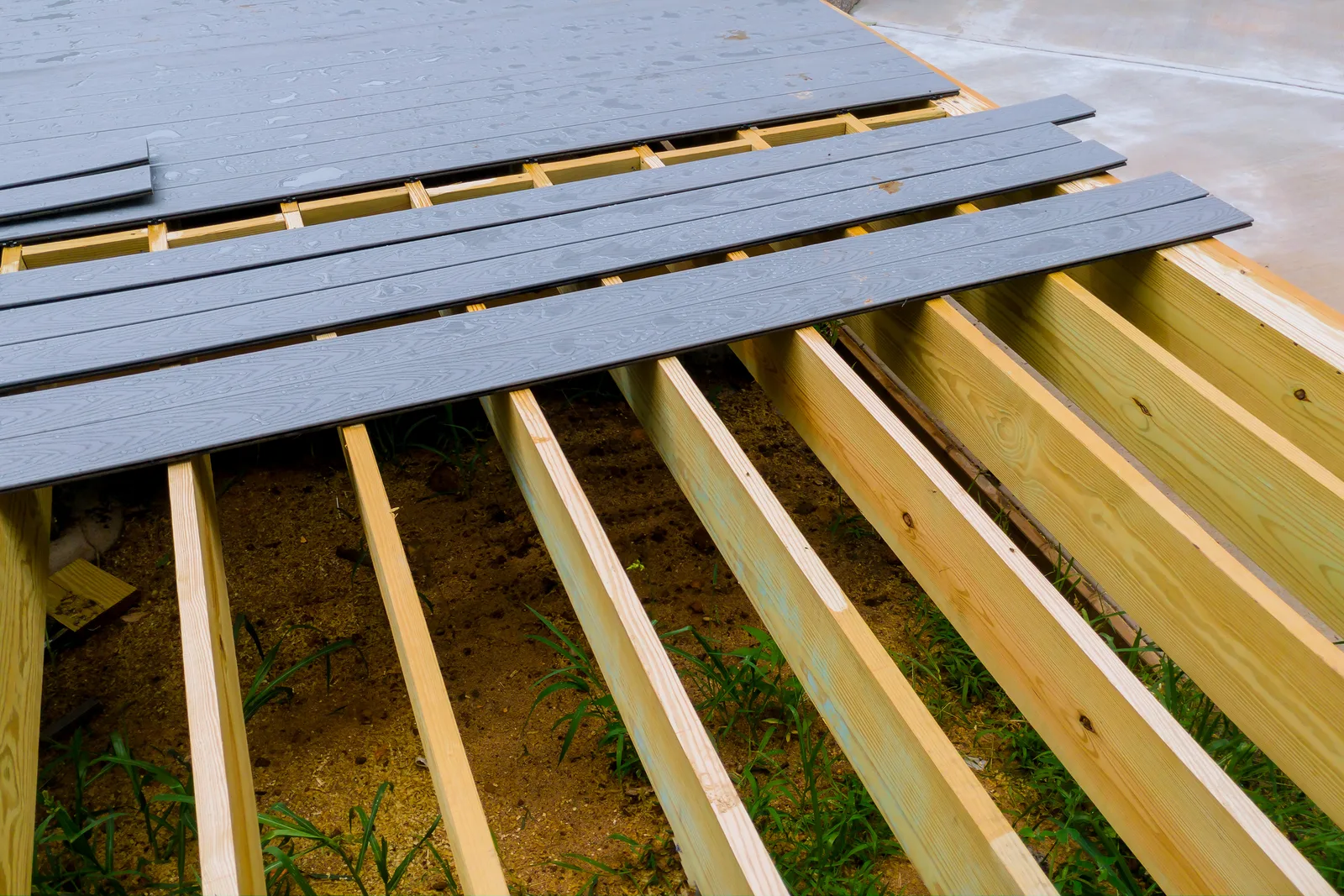 Deck builder fastening composite deck boards on a new backyard deck frame