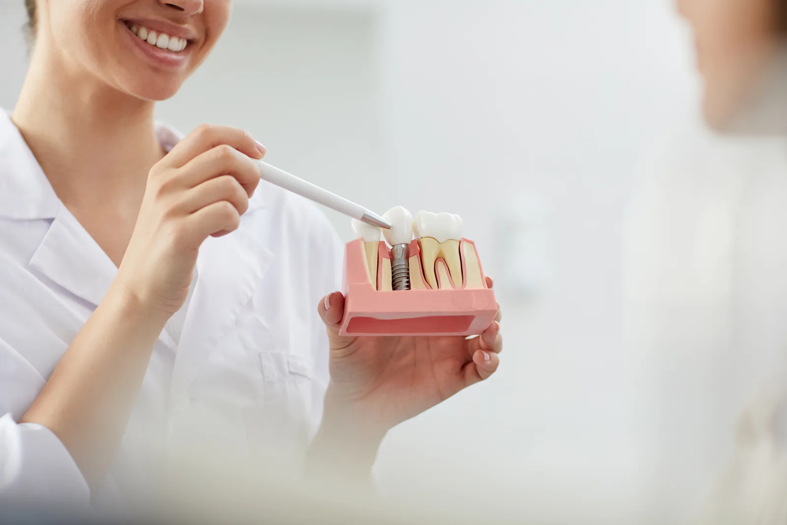 Dentist showing a patient a dental implant model during a consultation in a treatment room