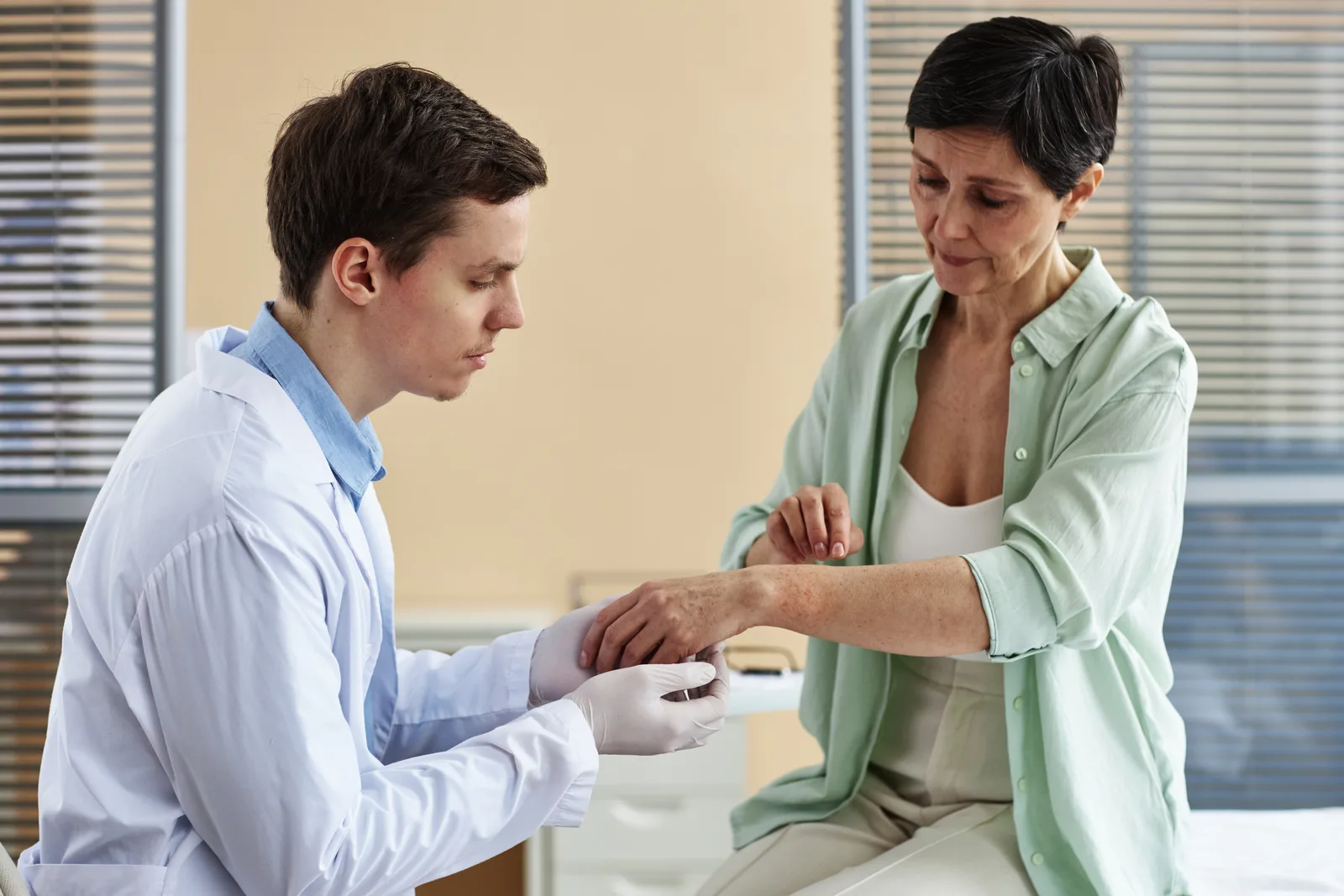 Dermatologist examining a patient's arm with a dermatoscope during a skin check
