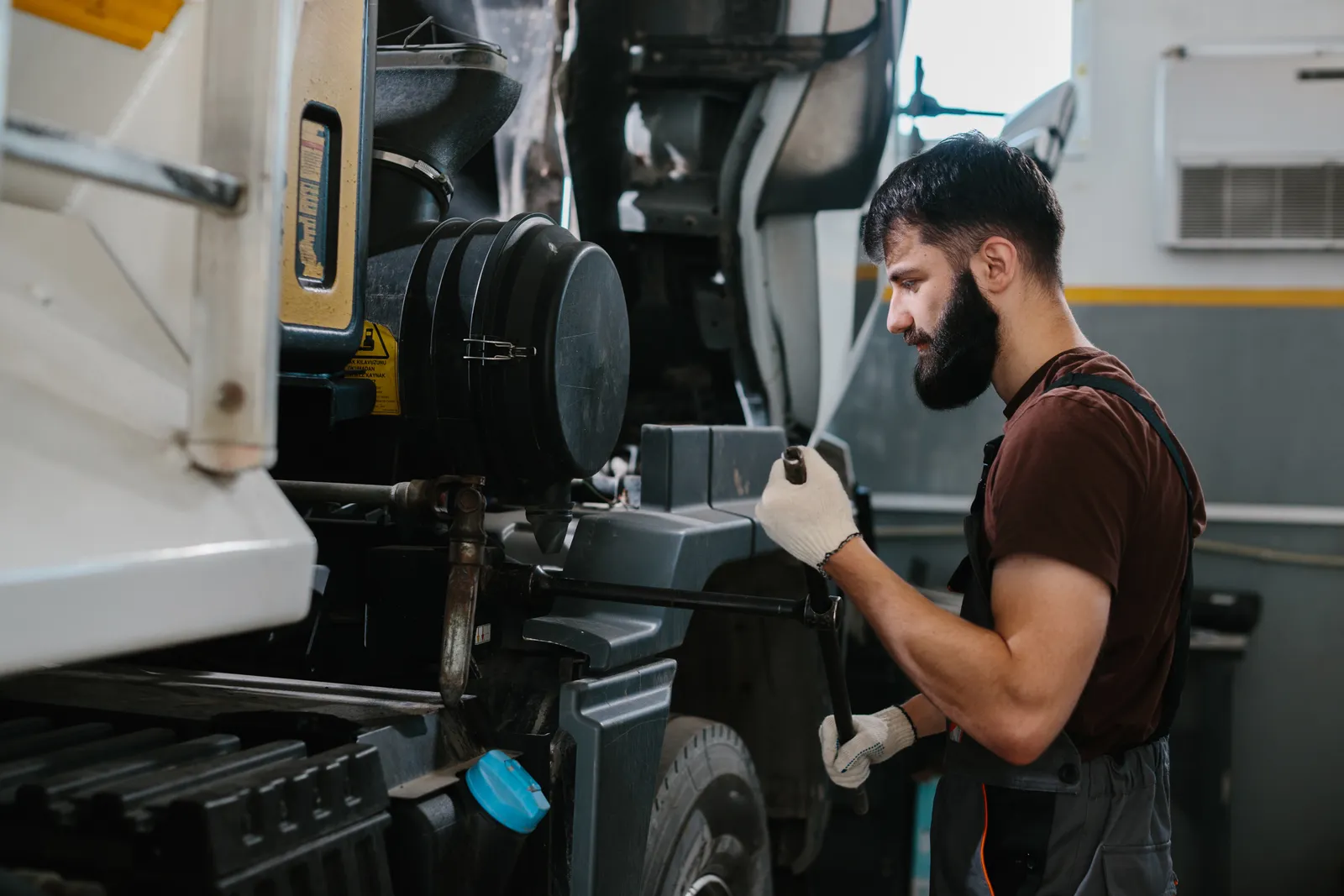Mechanic working on a semi truck's diesel engine in a repair bay