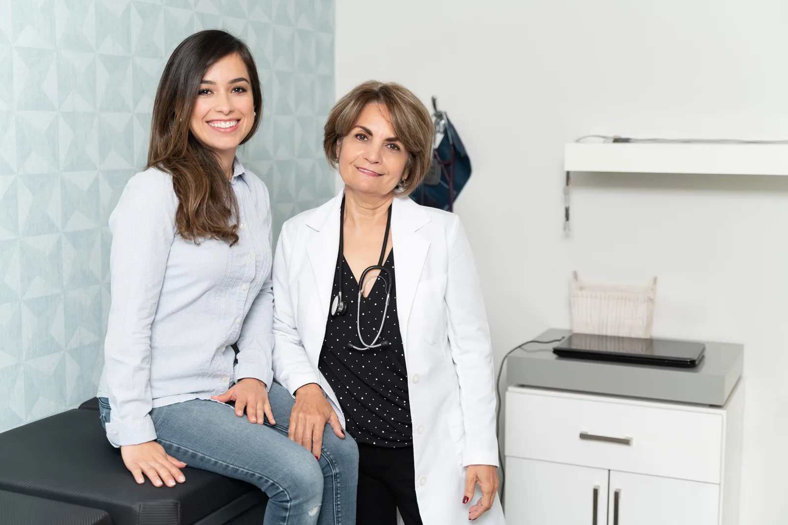 Direct primary care doctor sitting across from a patient during an unhurried appointment, reviewing their care plan together in a modern exam room