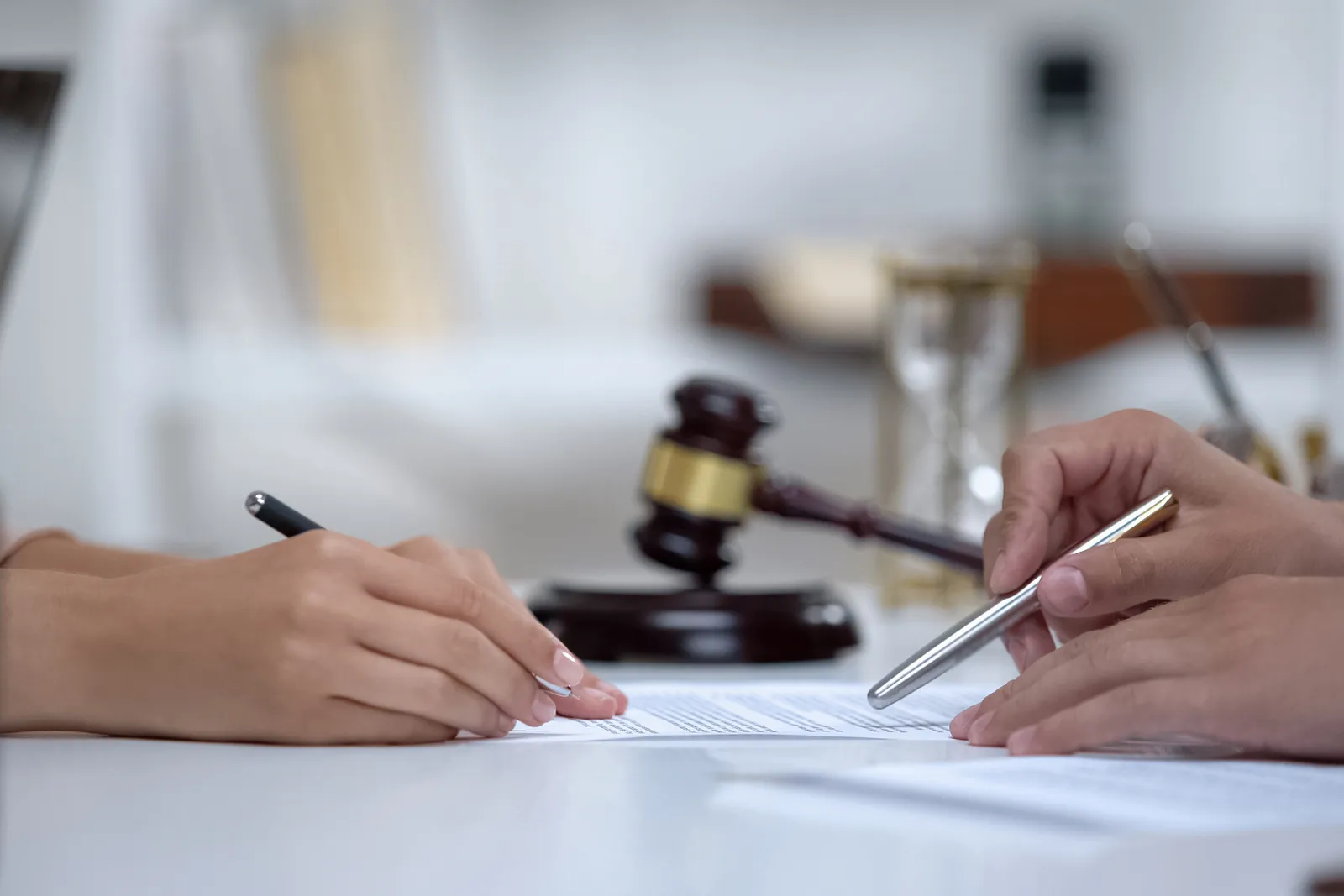 Defense attorney and client signing case documents beside a gavel