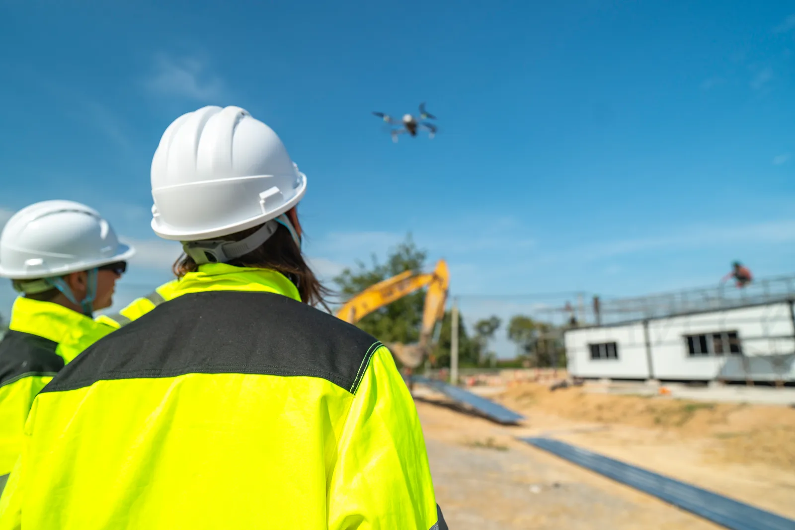 Commercial drone pilot flying a quadcopter over a construction site to capture aerial survey footage