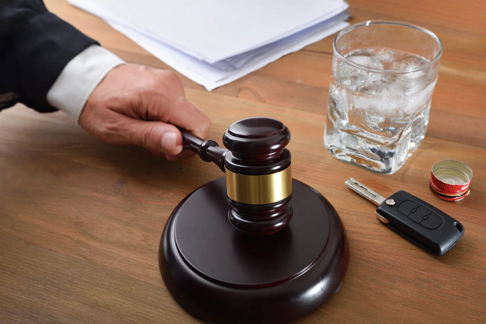 Gavel beside a whiskey glass and car keys, representing a drunk driving injury case