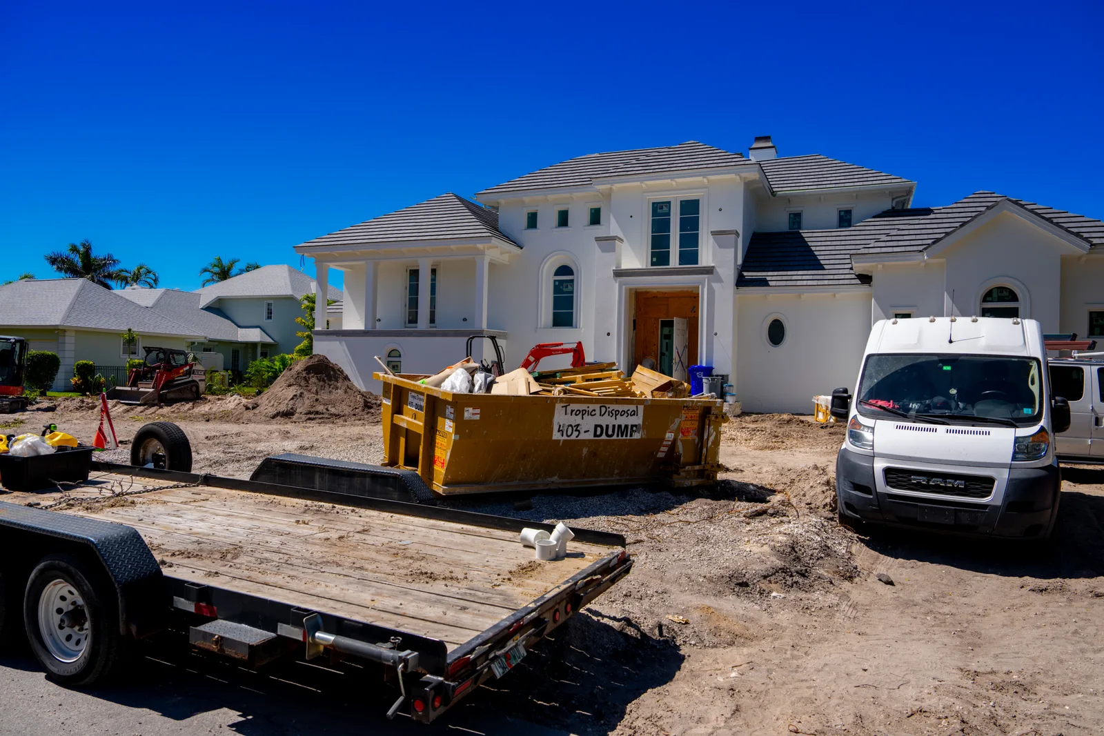 Roll-off truck lowering a rental dumpster onto a home's driveway before a renovation