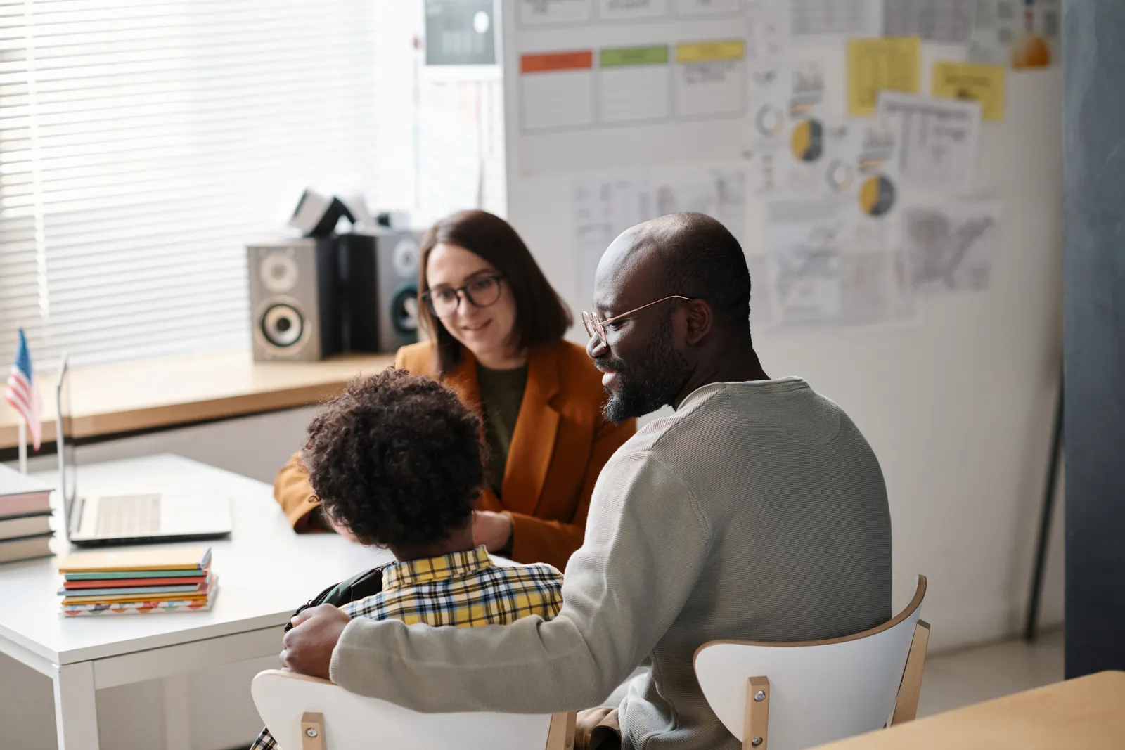 Father and his child meeting with a teacher in a classroom