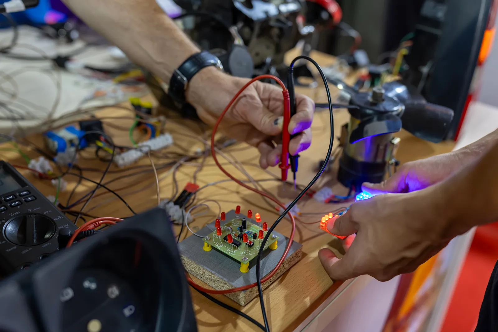 Engineer testing a circuit board with multimeter probes on a workbench