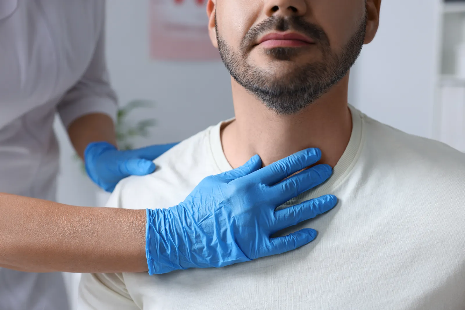 Endocrinologist examining a patient's thyroid by palpating the neck during an office visit