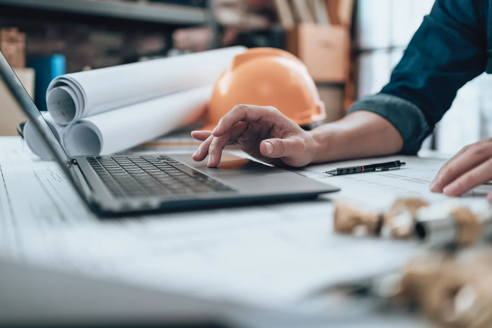 A structural engineer reviewing stamped drawings with a colleague at a desk in an engineering office
