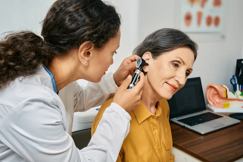 ENT doctor examining a patient's ear with an otoscope