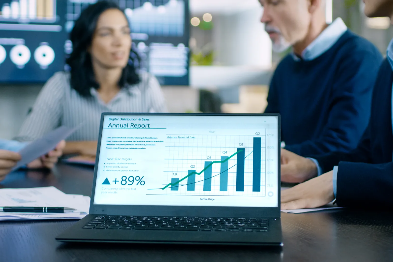 Enterprise software team reviewing a sales pipeline dashboard together on a laptop in a conference room