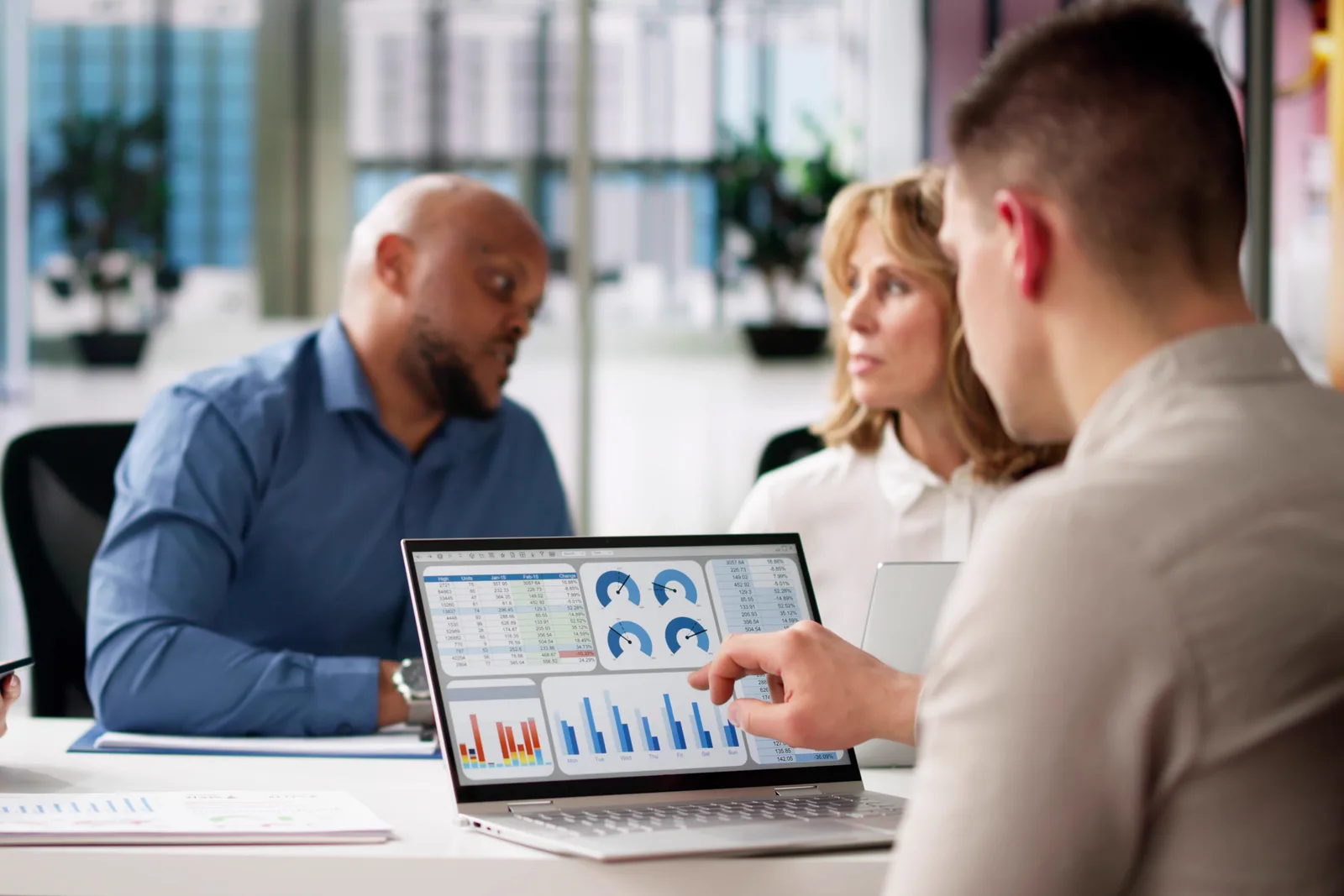 Equipment rental software team reviewing a fleet-utilization dashboard together at a laptop in their office