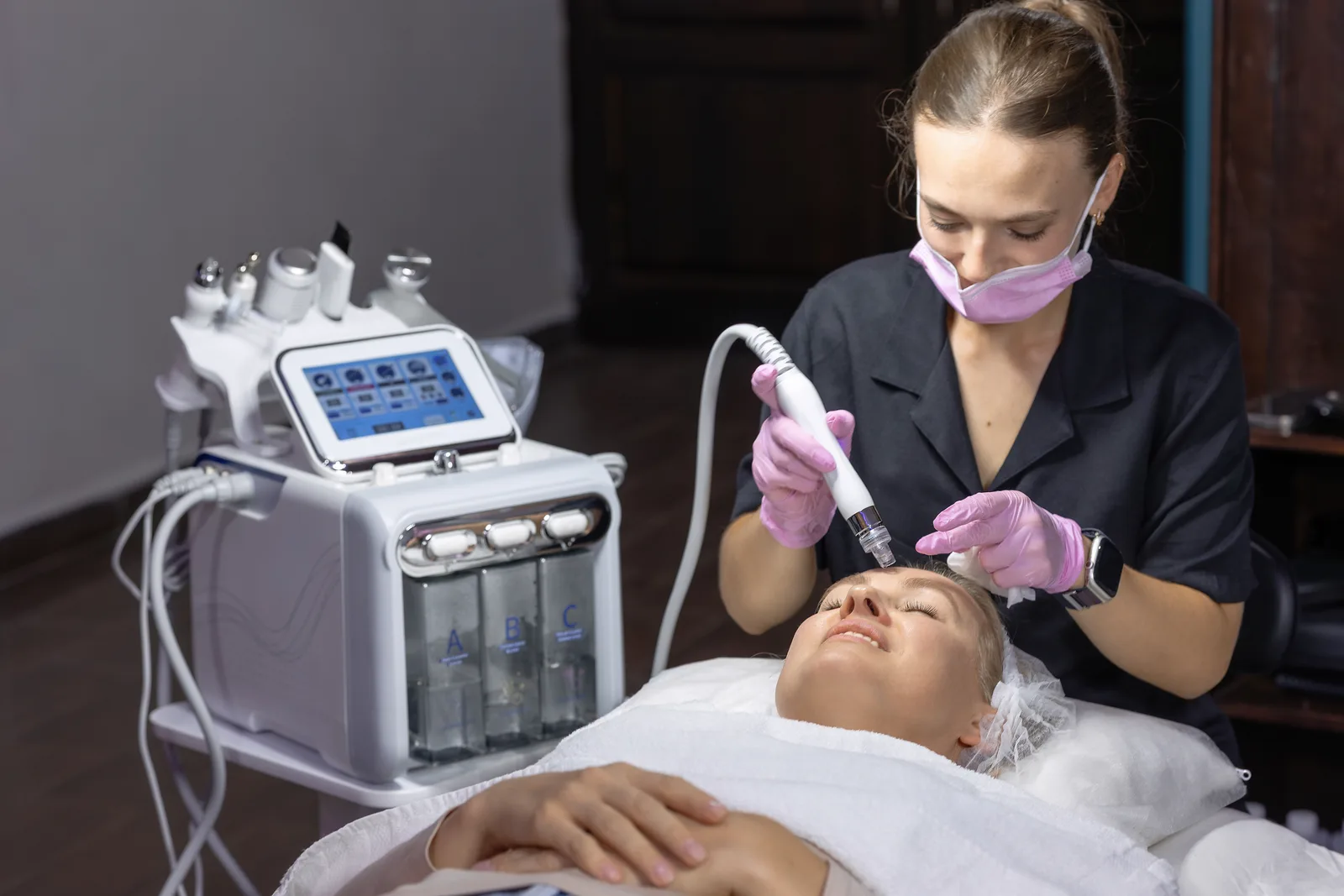 An independent esthetician performing a facial treatment on a client in a private treatment suite