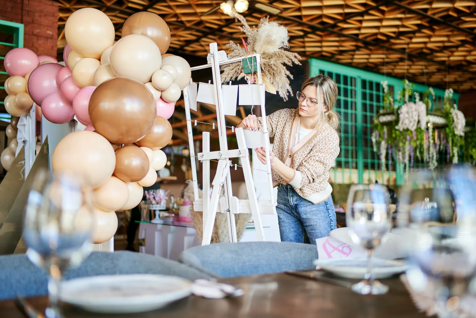 Event planner adjusting a table centerpiece in a decorated reception hall