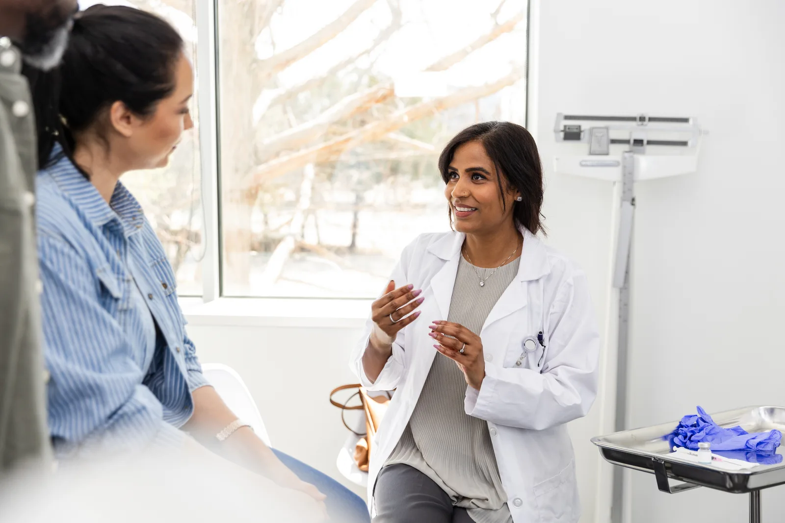 A couple in a consultation room talking through IVF options with their fertility specialist