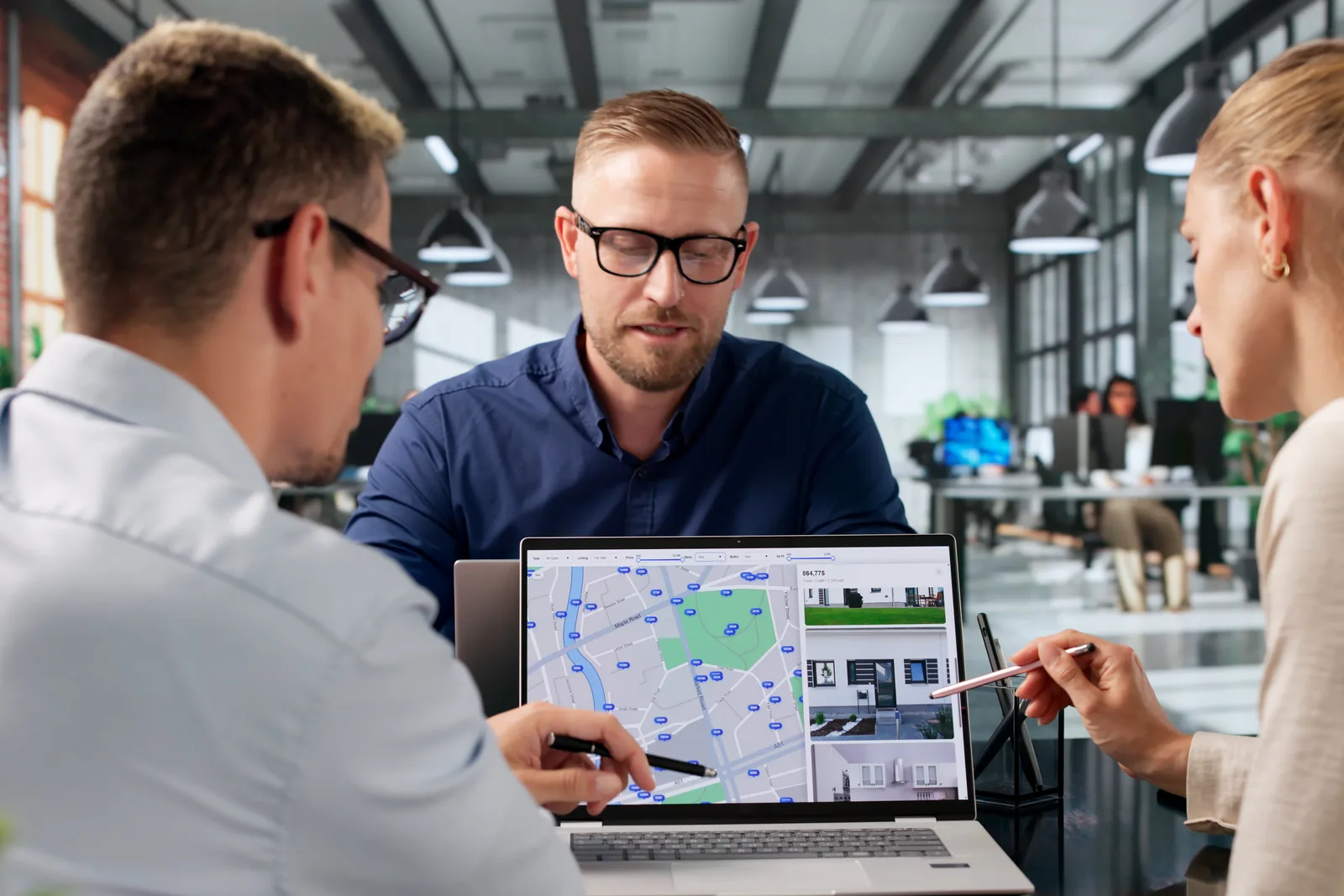 Software team reviewing a technician dispatch map and job schedule together at a laptop in their office