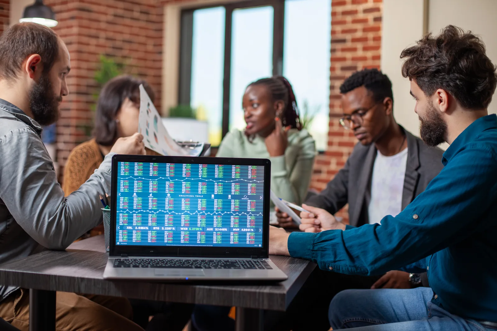 Fintech product team reviewing signup and conversion metrics together at a laptop in their office