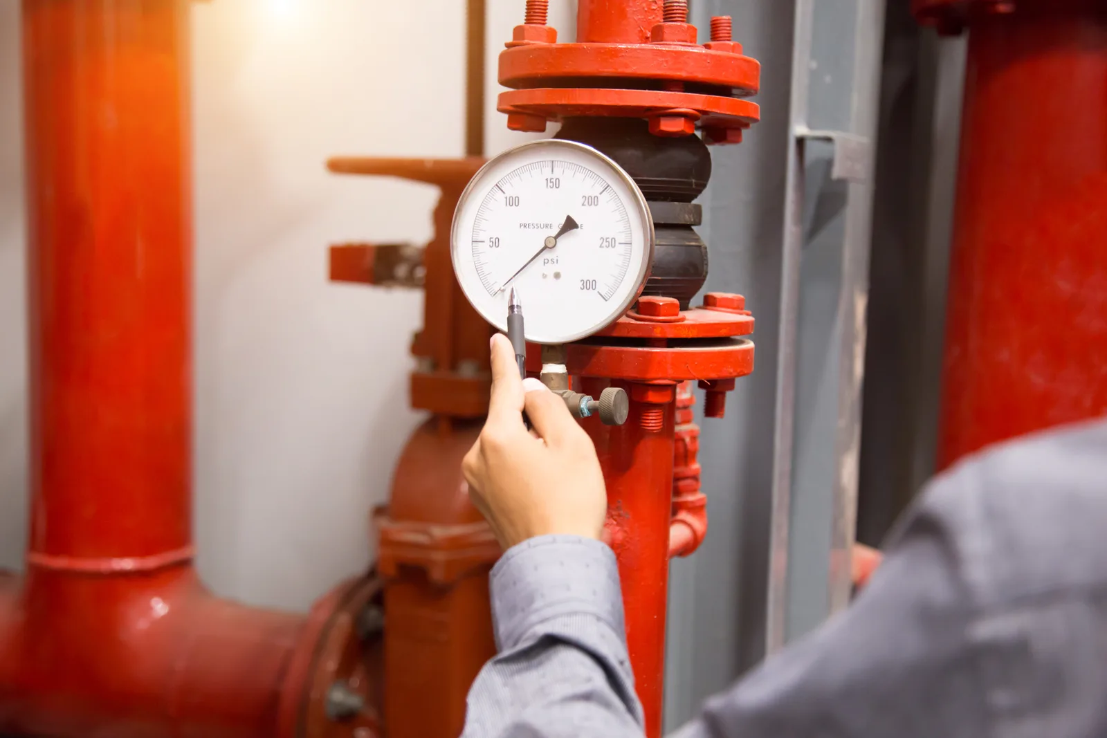 Fire protection technician inspecting a commercial sprinkler system's control valve and pressure gauges
