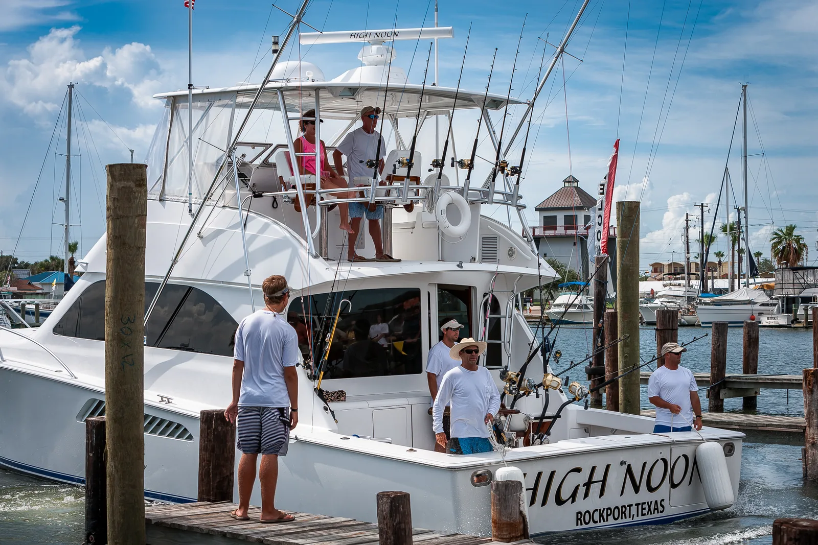Captain and anglers holding up a freshly caught fish on the deck of a charter fishing boat on open water