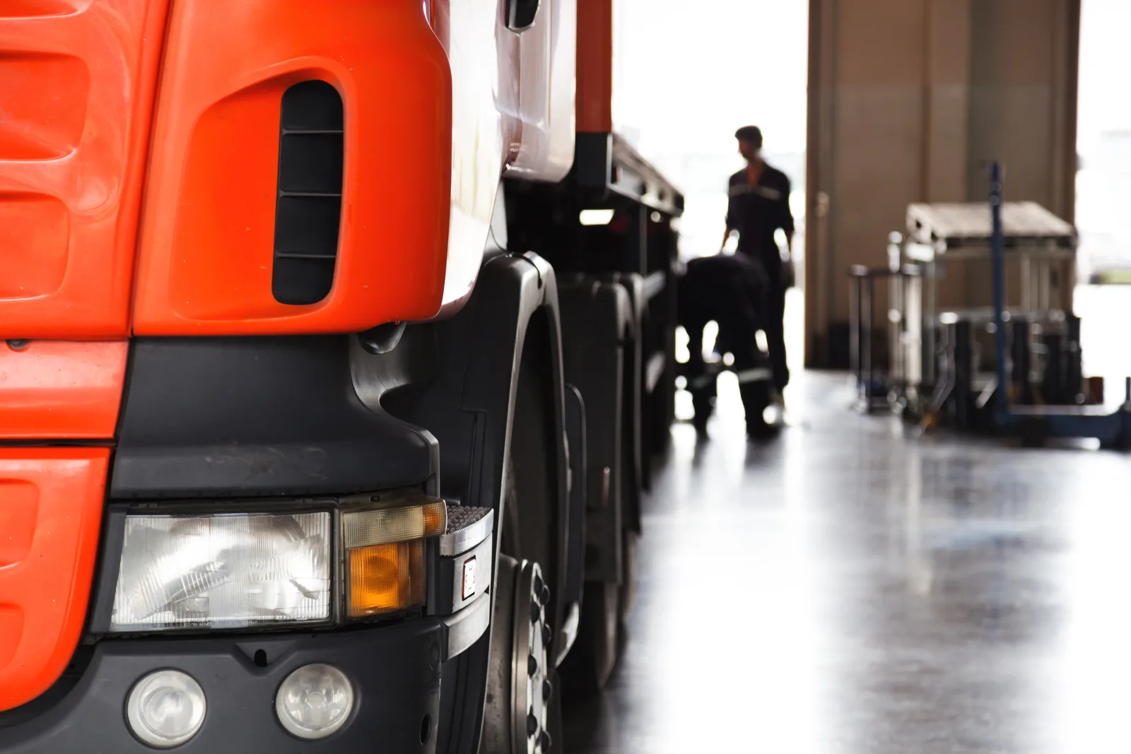 Commercial semi truck parked inside a fleet service facility with a technician in the background