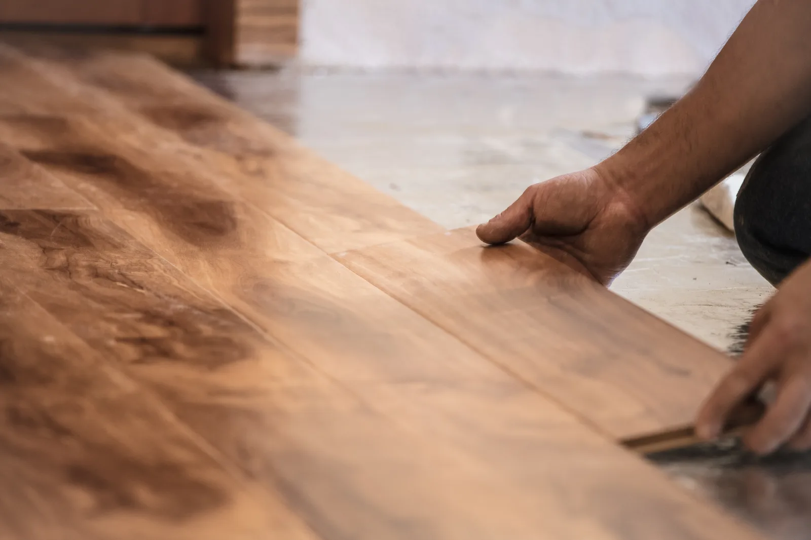 Installer tapping a hardwood plank into place in a customer's living room