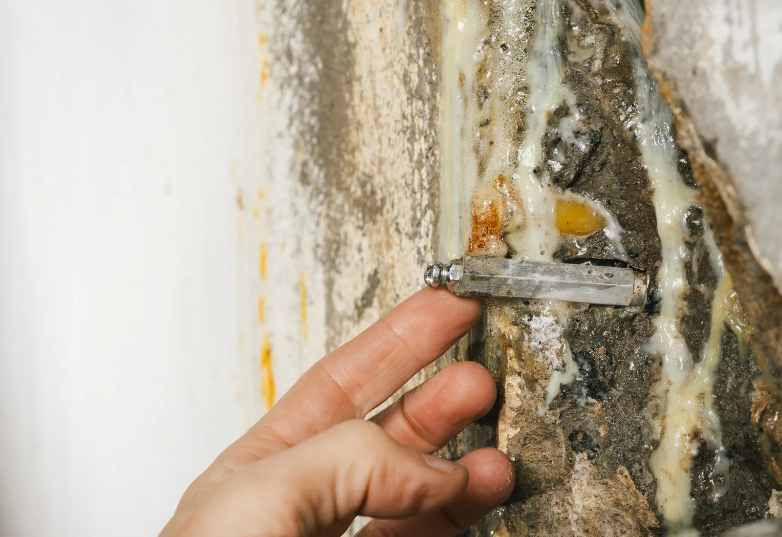 Structural inspector examining a stair-step crack in a home's basement foundation wall