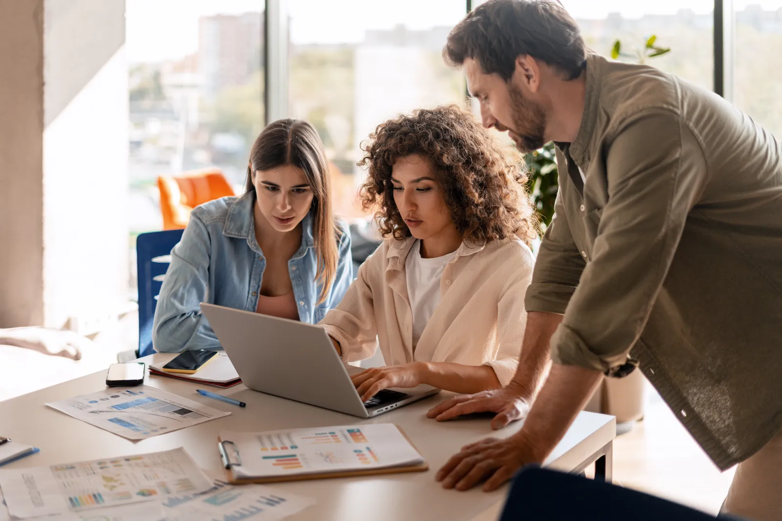 Freelance marketplace team reviewing growth charts together around a laptop in a bright office